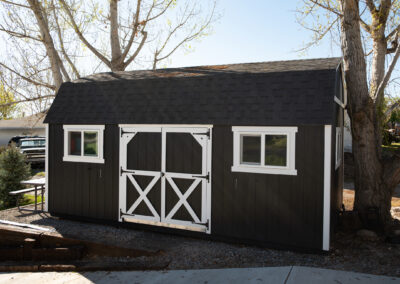 Black barn-style storage shed with white trim