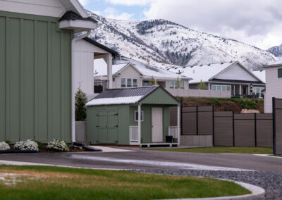 Green a-frame style shed with white door and porch railing