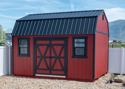 Red barn-style shed with black roof and trim