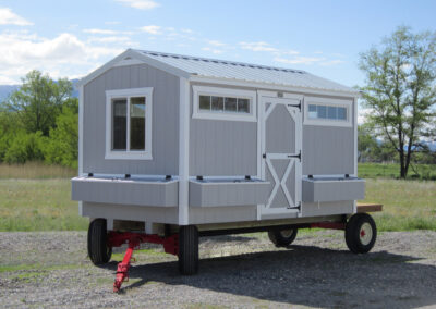 Gray A-frame chicken coop with white trim on a trailer